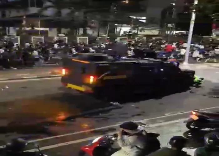 Tangkapan layar video Sebuah kendaraan taktis Brimob terekam kamera melaju kencang menerobos kerumunan massa aksi dan menabrak dua pengemudi ojek online (ojol). | f. Tangkapan Layar Video yang Beredar